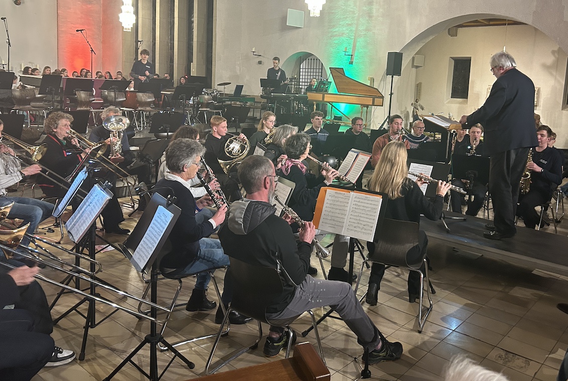 Mann dirigiert Bigband aus Jugendlichen und Erwachsenen in einer Kirche