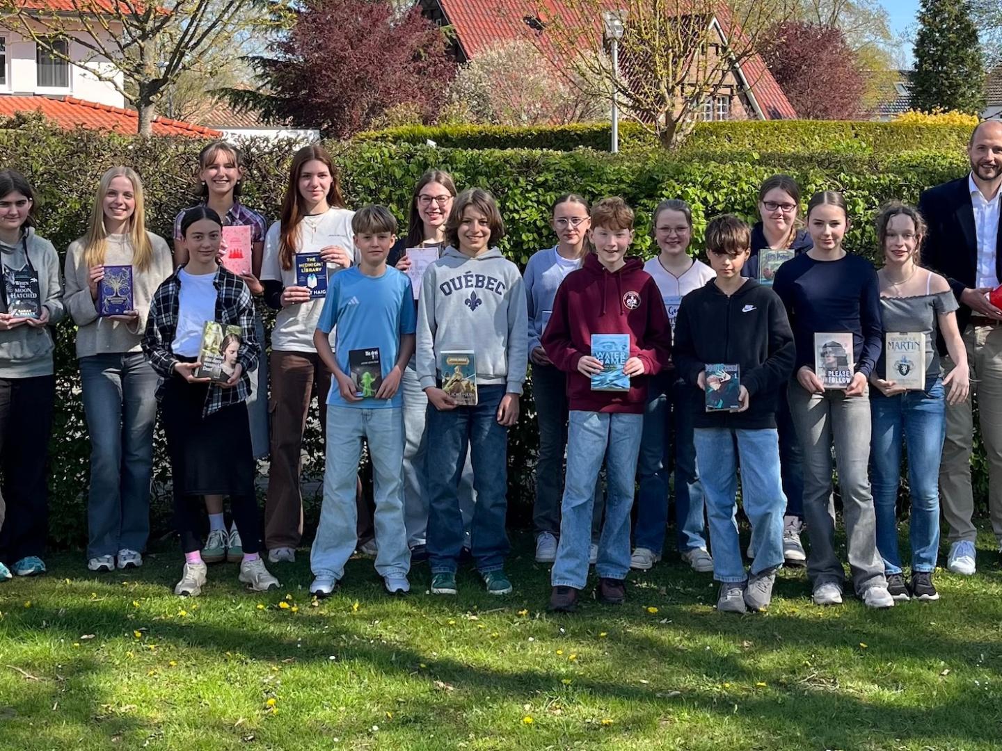 Gruppenfoto Schülerinnen und Schüler, Bücher in den Händen, seitlich jeweils Erwachsene