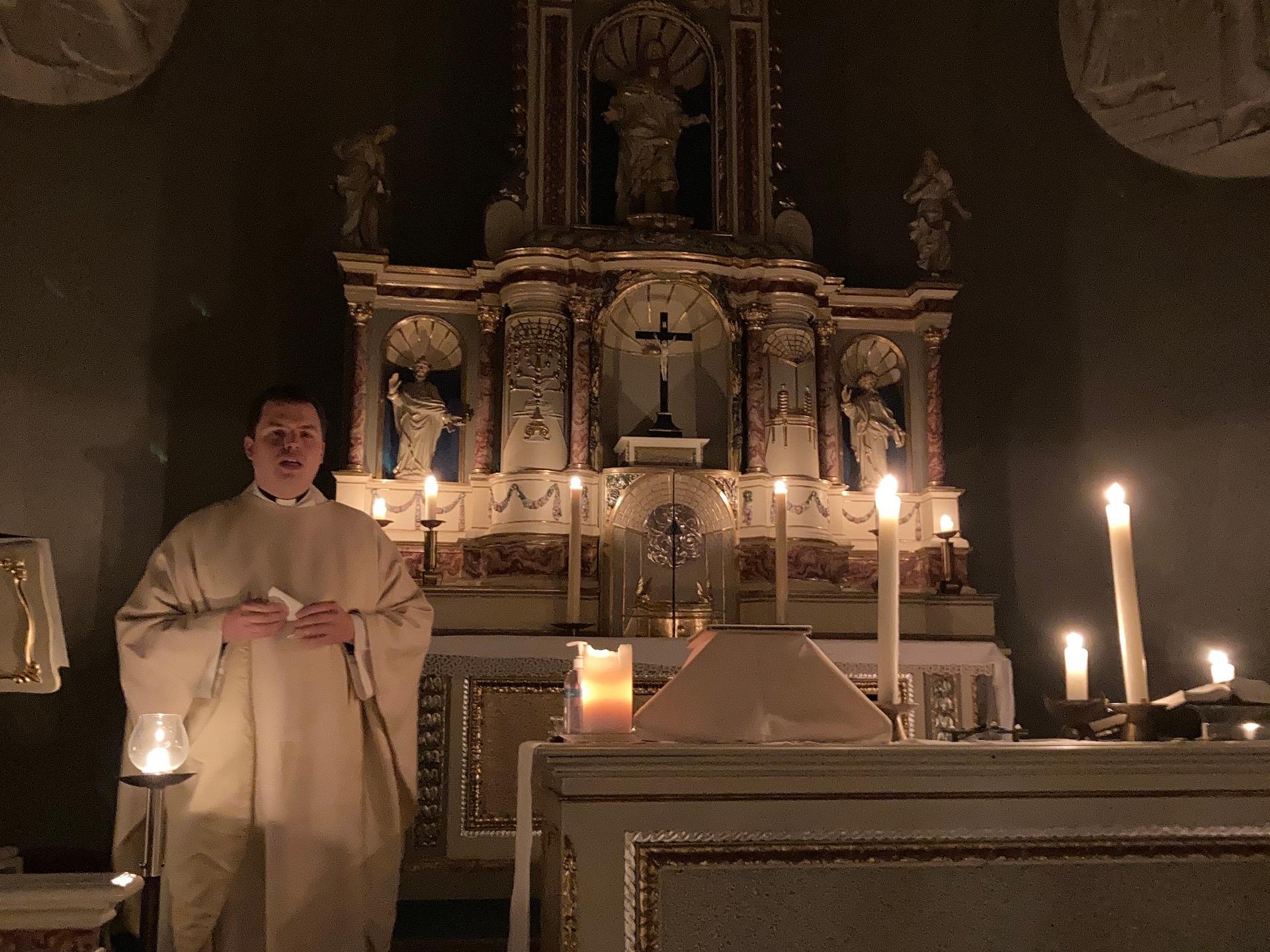 Priester vor mit Kerzen erleuchtetem Altar