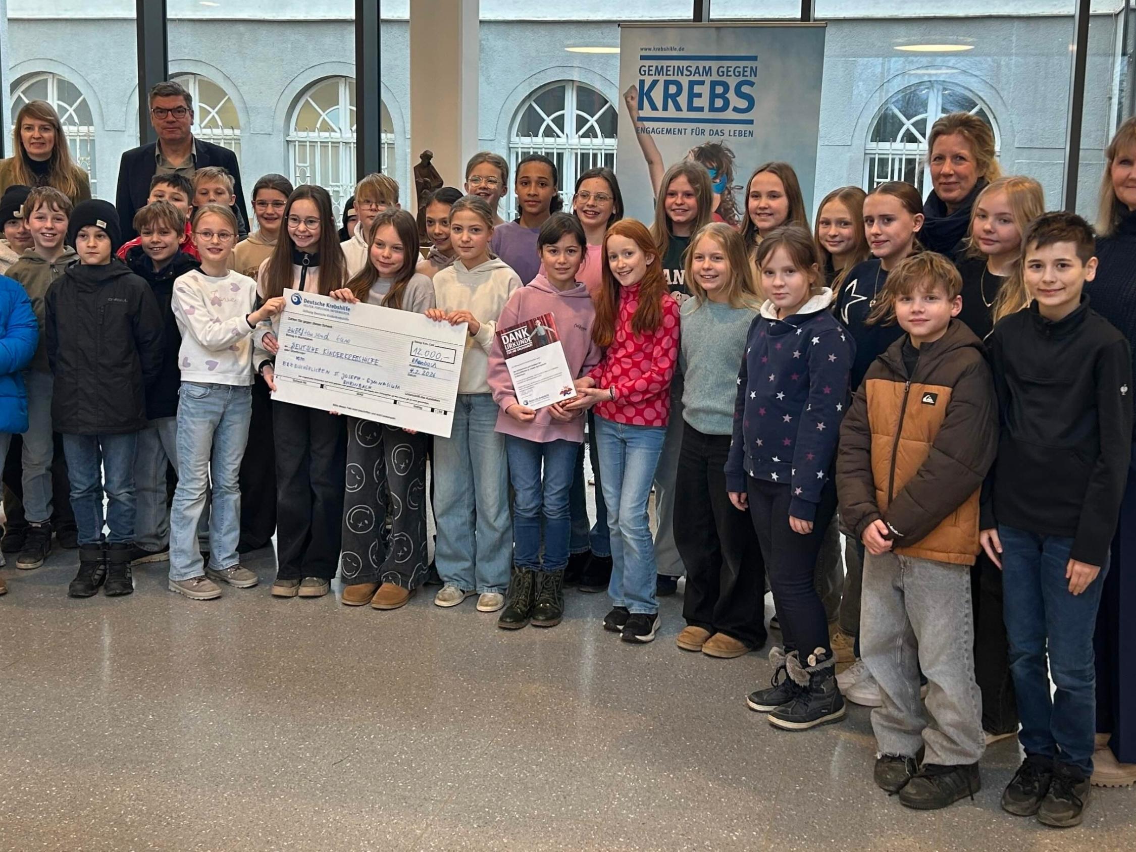 Gruppenfoto mit Kindern und Erwachsene, im Vordergrund ein großer Scheck