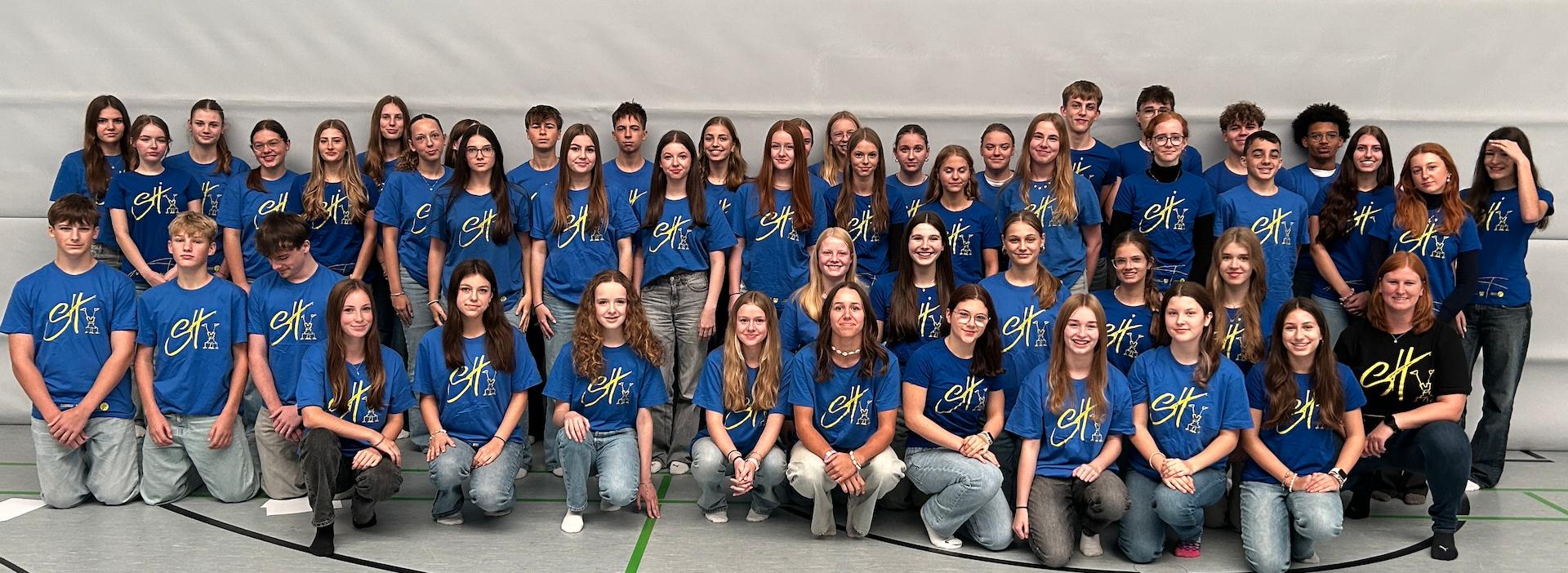 Mädchen und Jungen mit T-Shirt mit Aufdruck 'Sporthelfer' in der Turnhalle