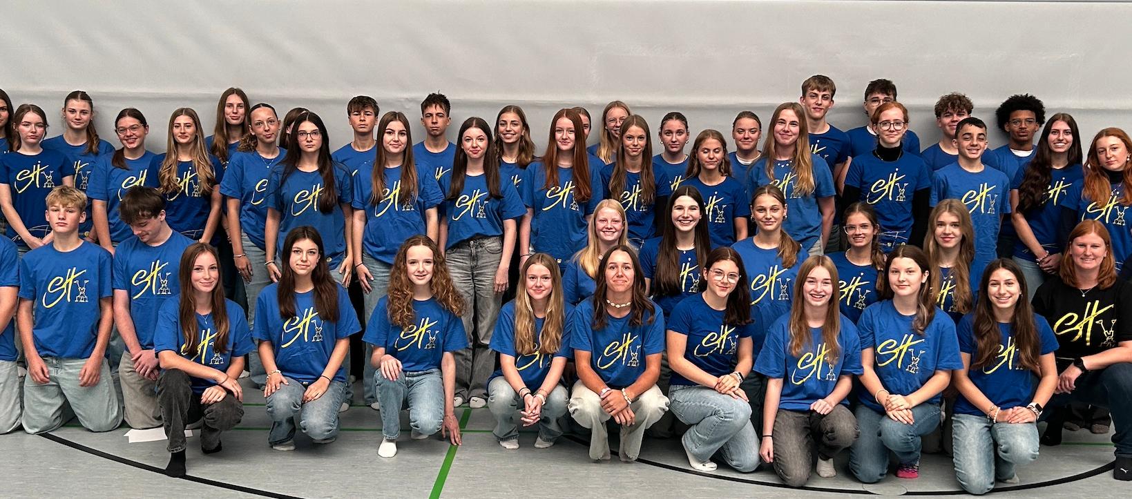 Mädchen und Jungen mit T-Shirt mit Aufdruck 'Sporthelfer' in der Turnhalle