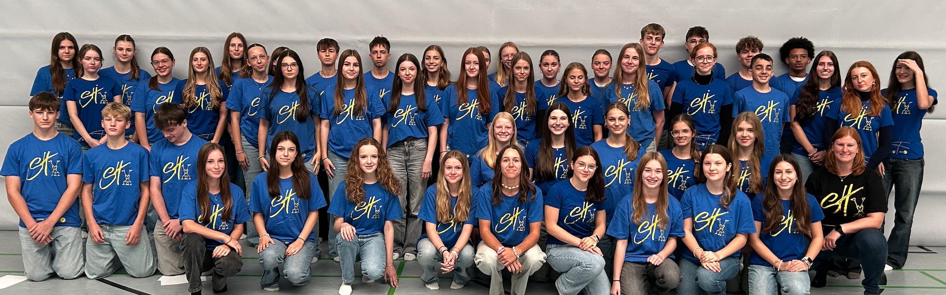 Mädchen und Jungen mit T-Shirt mit Aufdruck 'Sporthelfer' in der Turnhalle