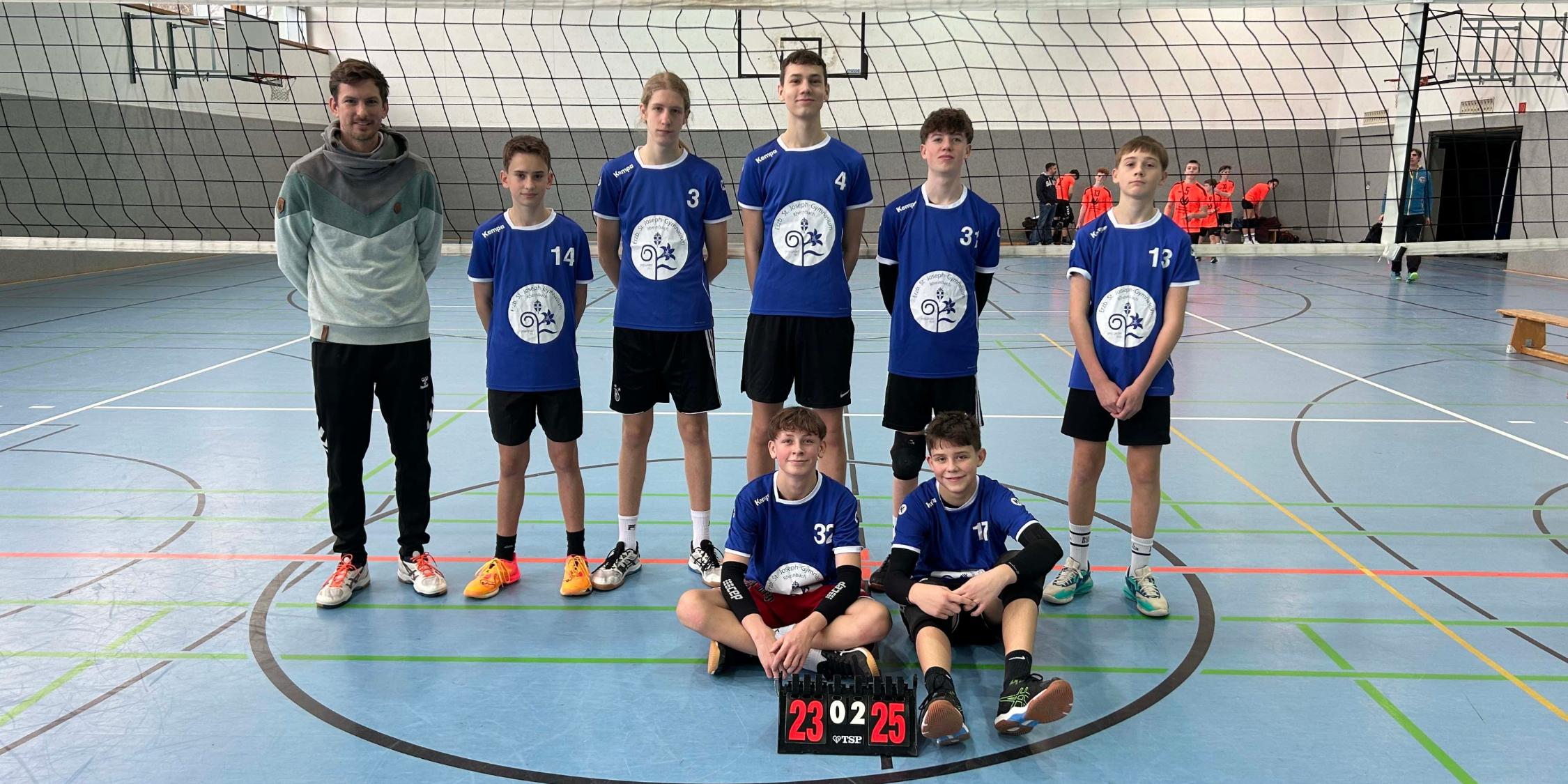 Jungen und Lehrer im Gruppenbild in der Sporthalle mit Volleyball